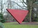 Red triangular sculpture, leaning against a tree in the park